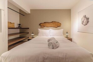 A bedroom with a bed, two bedside lamps, a wooden headboard, a wall-mounted artwork, and a shelf with a woven basket. - Elegant Angamos Oeste Residence By Geko (Miraflores)