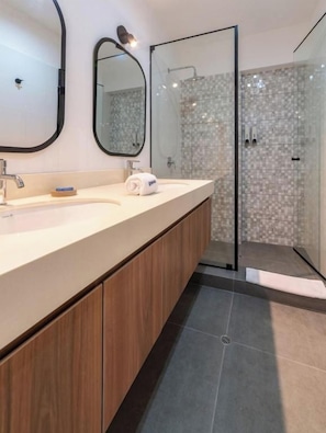 A modern bathroom with a wooden vanity, a glass shower enclosure, and a tiled shower area. - José Gonzales 626 Apartments Near Kennedy Park By Geko (Miraflores)