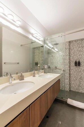 A modern bathroom with two sinks, a large mirror, and a glass-enclosed shower area. - José Gonzales 626 Apartments Near Kennedy Park By Geko (Miraflores)