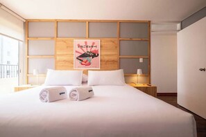 A hotel room with a large bed, a wooden headboard, and a poster on the wall. - Urban Schell Miraflores Apartment By Geko (Miraflores)