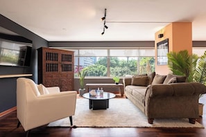 A modern living room with a sofa, armchair, coffee table, and a bookshelf. - Urban Schell Miraflores Apartment By Geko (Miraflores)