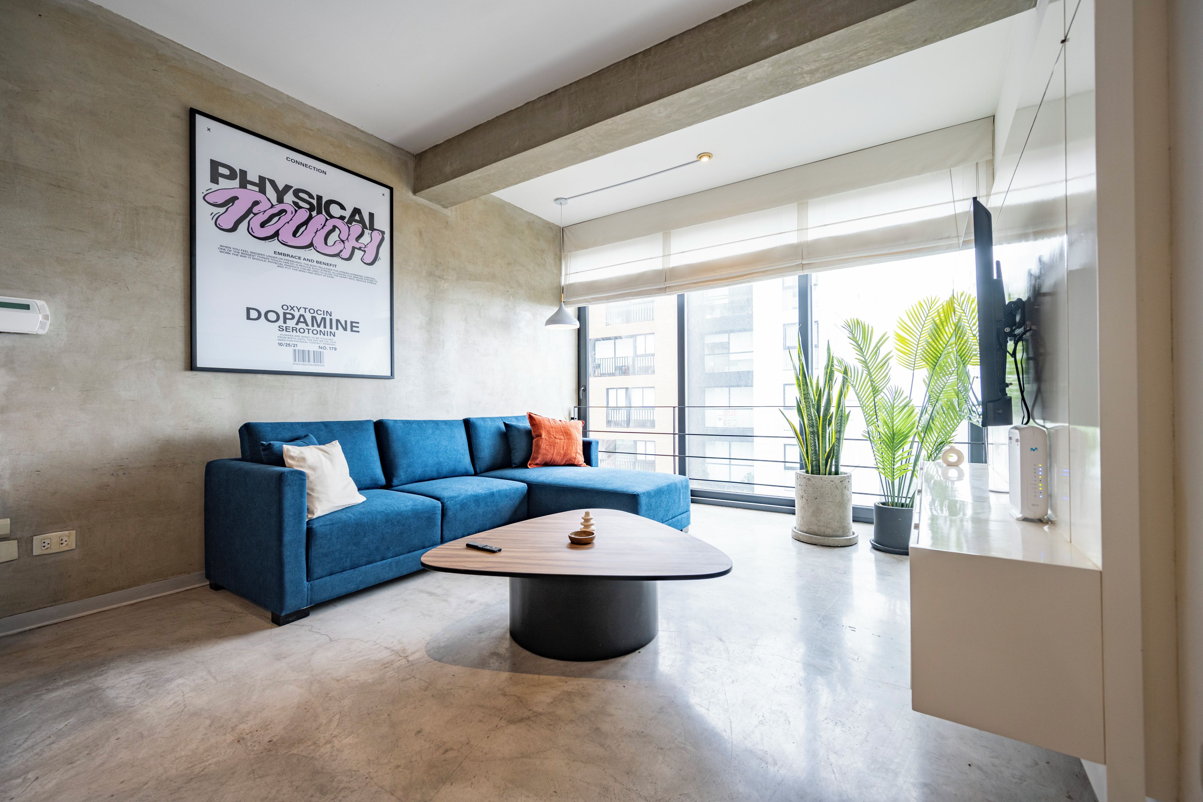 A modern living room with a blue sofa, a round coffee table, and a large poster on the wall.