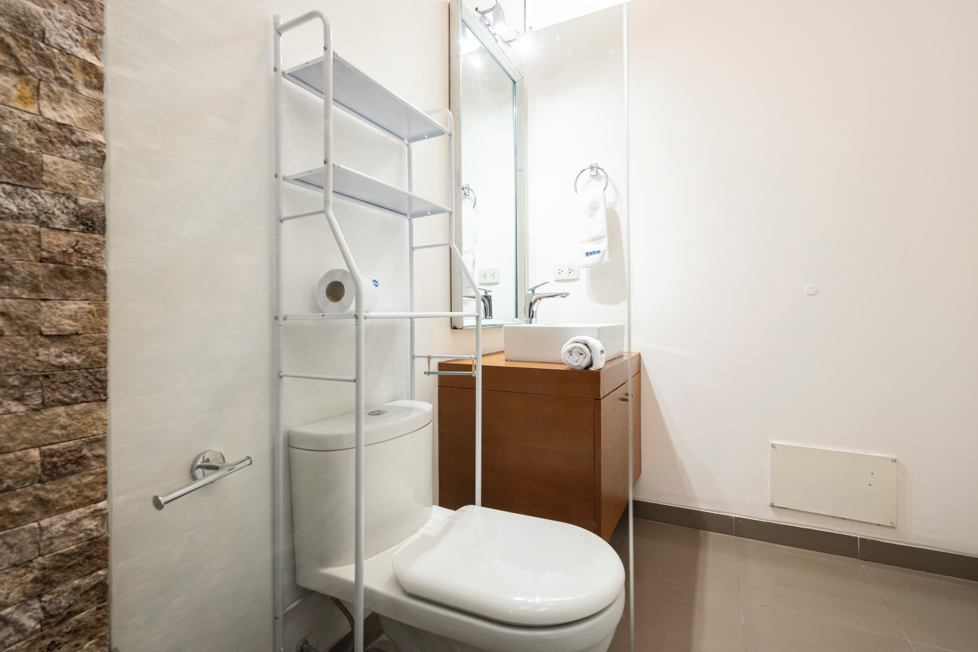 A bathroom with a toilet, a sink, a mirror, and a towel rack.