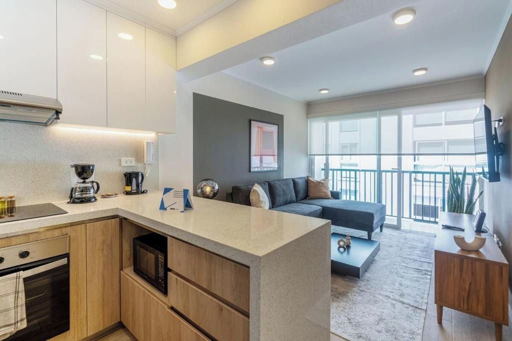 A modern kitchen with a built-in microwave, a coffee maker, and a small island counter.