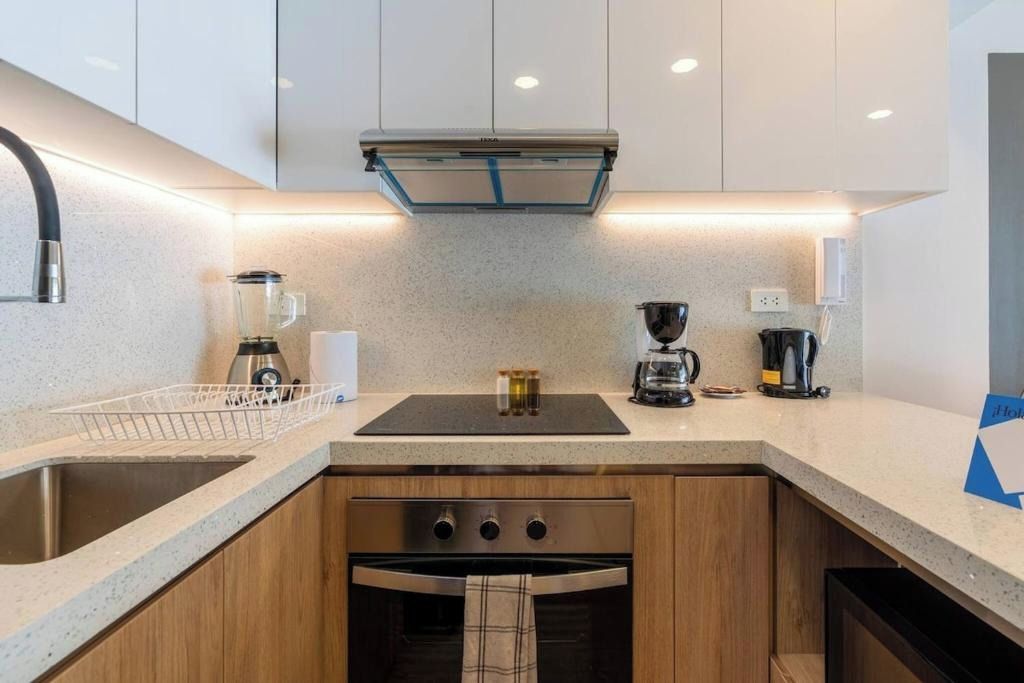 A modern kitchen with a stainless steel sink, a built-in oven, and a coffee maker.