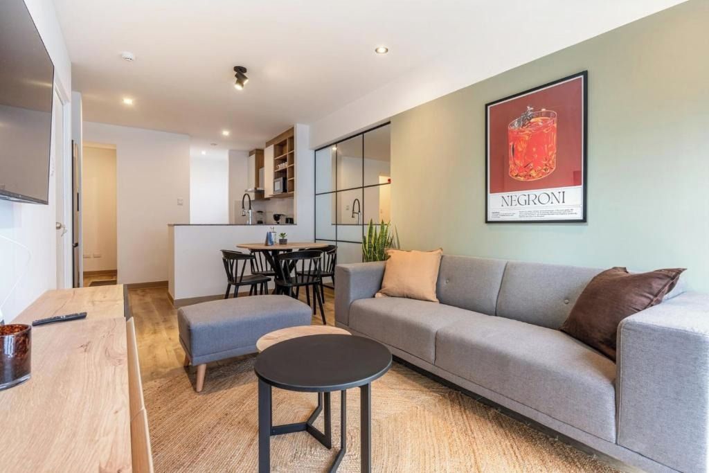 Un salon moderne avec un canapé gris, une petite table ronde et un coin repas comprenant une table et des chaises.