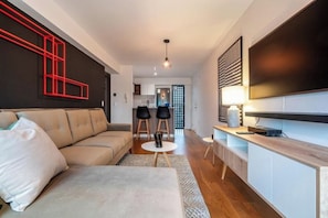 A modern living room with a sofa, a coffee table, and a TV mounted on the wall. - Suárez Signature Apartment By Geko (San Isidro)