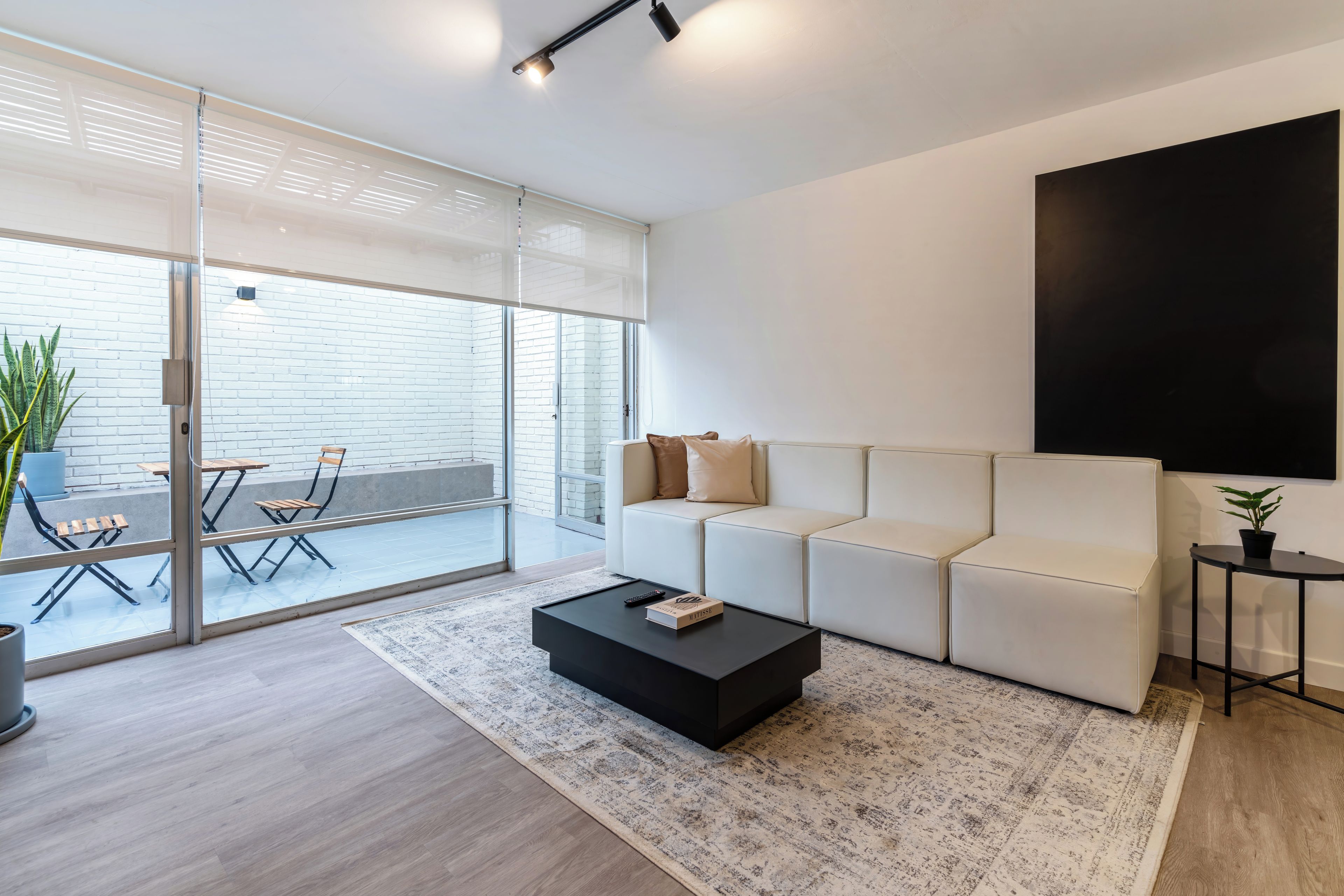 A modern living room with a sofa, a coffee table, and a large window.