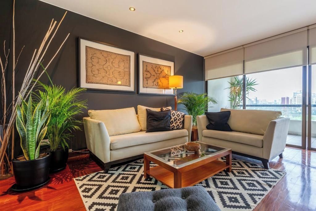 Ein modernes Wohnzimmer mit zwei Sofas, einem Couchtisch und dekorativen Pflanzen.