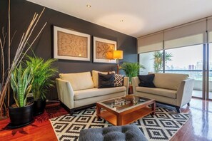 A modern living room with two sofas, a coffee table, and decorative plants. - Coronel Portillo Residences By Geko (San Isidro)