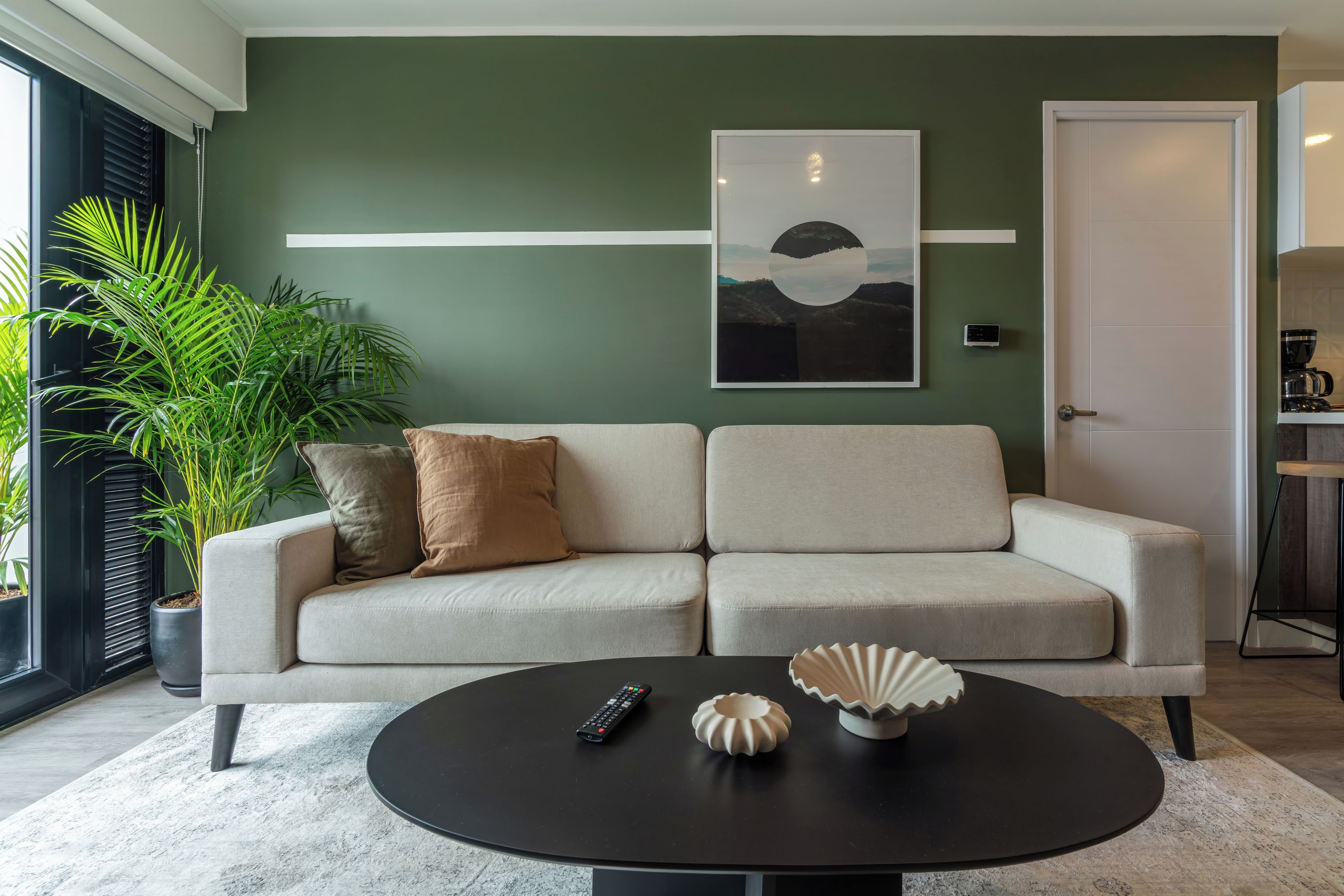 A modern living room with a sofa, a coffee table, and a large window with blinds.
