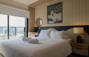 Ein Hotelzimmer mit einem großen Bett, einem Nachttisch, einer Lampe, einem Spiegel und einem Gemälde an der Wand.