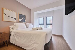 A modern bedroom with a bed, bedside tables, and artwork on the wall. - Modern 2Br Apartment With Pool, Gym & Coworking (Miraflores)