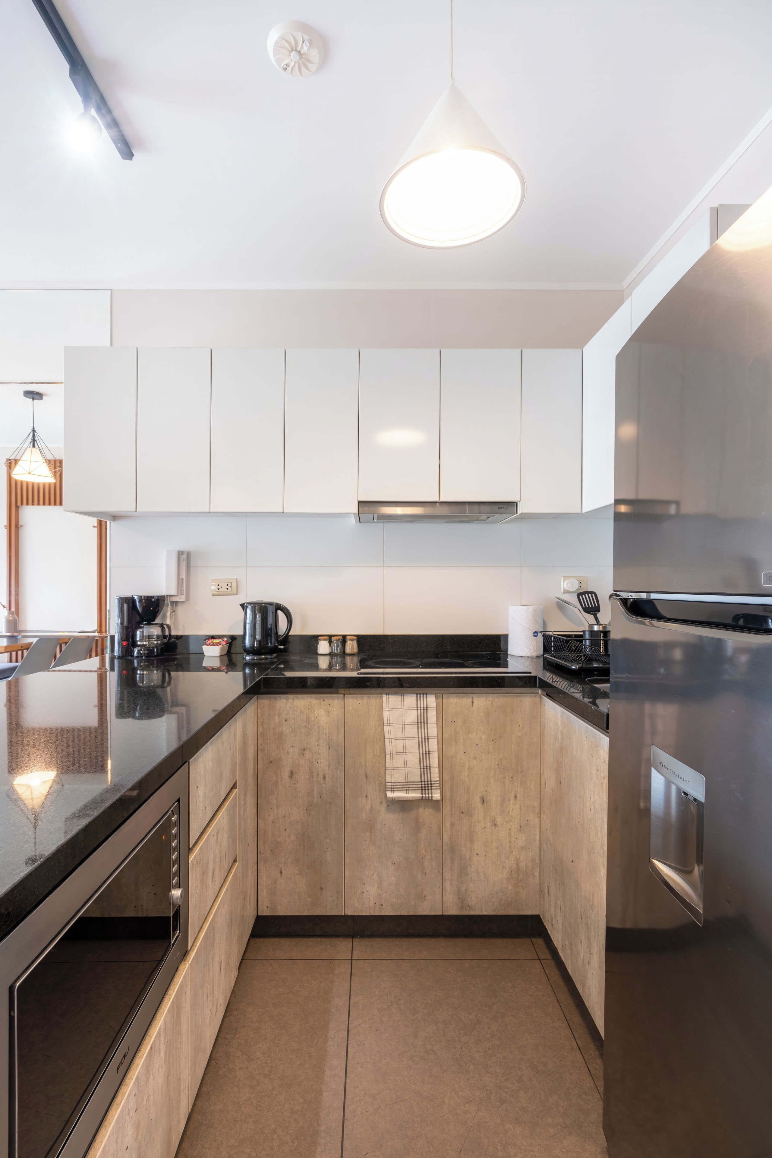 A modern kitchen with a black countertop, stainless steel appliances, and white cabinetry.