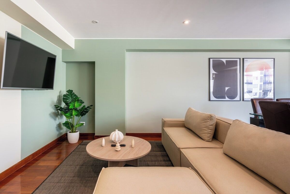 A living room with a sofa, a coffee table, a TV, and a potted plant.