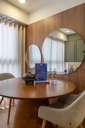 A round wooden table with a mirror, two chairs, a blue informational card, and a small decorative item. - Ejército City Lofts & Apartments By Geko (Miraflores)