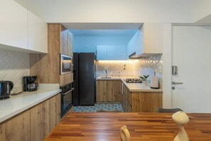 A compact kitchen with wooden cabinets, a black refrigerator, and a countertop with a coffee maker. - Elegant Los Angeles Apartments By Geko (San Isidro)