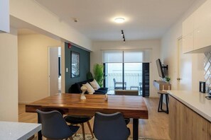 A modern kitchen with a wooden dining table, black chairs, and a view to the outside. - Elegant Los Angeles Apartments By Geko (San Isidro)