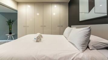 A modern bedroom with a large bed, a small round table, and a potted plant.