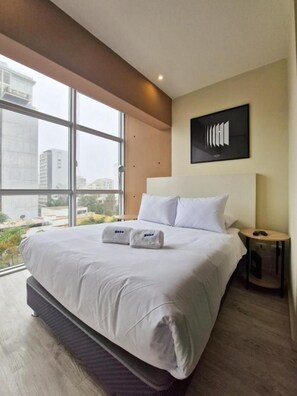 Ein modernes Hotelzimmer mit einem großen Bett, Blick durch das Fenster und einem an der Wand befestigten Kunstwerk.