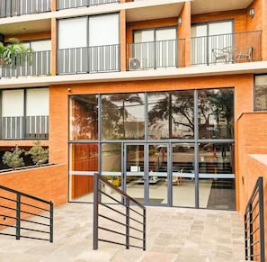 A multi-story building with a modern design, featuring balconies with metal railings and a large glass entrance. - Javier Prado Executive Apartments By Geko (Lima)