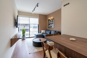 Een moderne woonruimte met een eethoek, een bank en een groot raam.