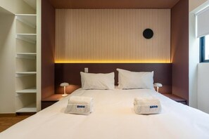 A hotel room with a bed, two bedside tables, a wall-mounted shelf, and a window. - Miraflores Canseco Apartments By Geko (Lima)