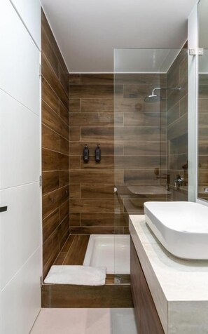 A modern bathroom with a glass shower enclosure, a bathtub, and a white sink. - Vasco Núñez Residence By Geko (Miraflores)