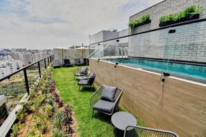 A rooftop pool area with a glass railing, seating, and a view of the cityscape. - La Mar Suites By Geko In Miraflores (Miraflores)