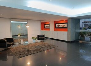 A modern lobby with a glass partition, seating area, and artwork on the walls. - Charming Dalias Apartments By Geko (Miraflores)