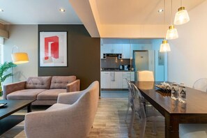 A modern living room with a sofa, a dining table, and a kitchen in the background. - Charming Dalias Apartments By Geko (Miraflores)