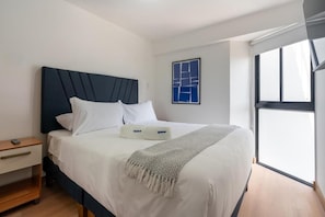 A hotel room with a bed, a nightstand, a window, and a wall art piece. - Arrieta 380 Suites By Geko (Barranco)