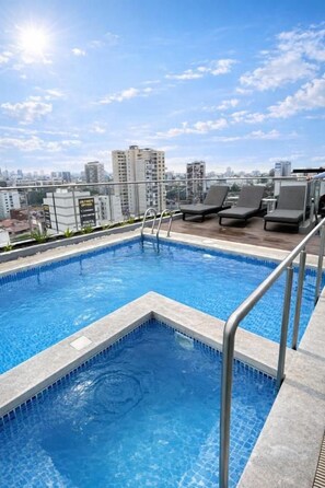 A rooftop pool with a cityscape view, a metal ladder, and lounge chairs. - Arrieta 380 Suites By Geko (Barranco)