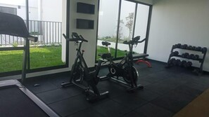 A gym with stationary bikes, a treadmill, and a rack of dumbbells. - Arrieta 380 Suites By Geko (Barranco)