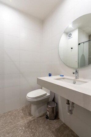 Ein Badezimmer mit Toilette, Waschbecken, Spiegel und gefliesten Wänden.