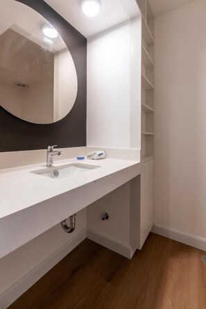A modern bathroom with a white sink, a round mirror, and a built-in shelf. - Solar Breezy Retreat By Geko (Barranco)