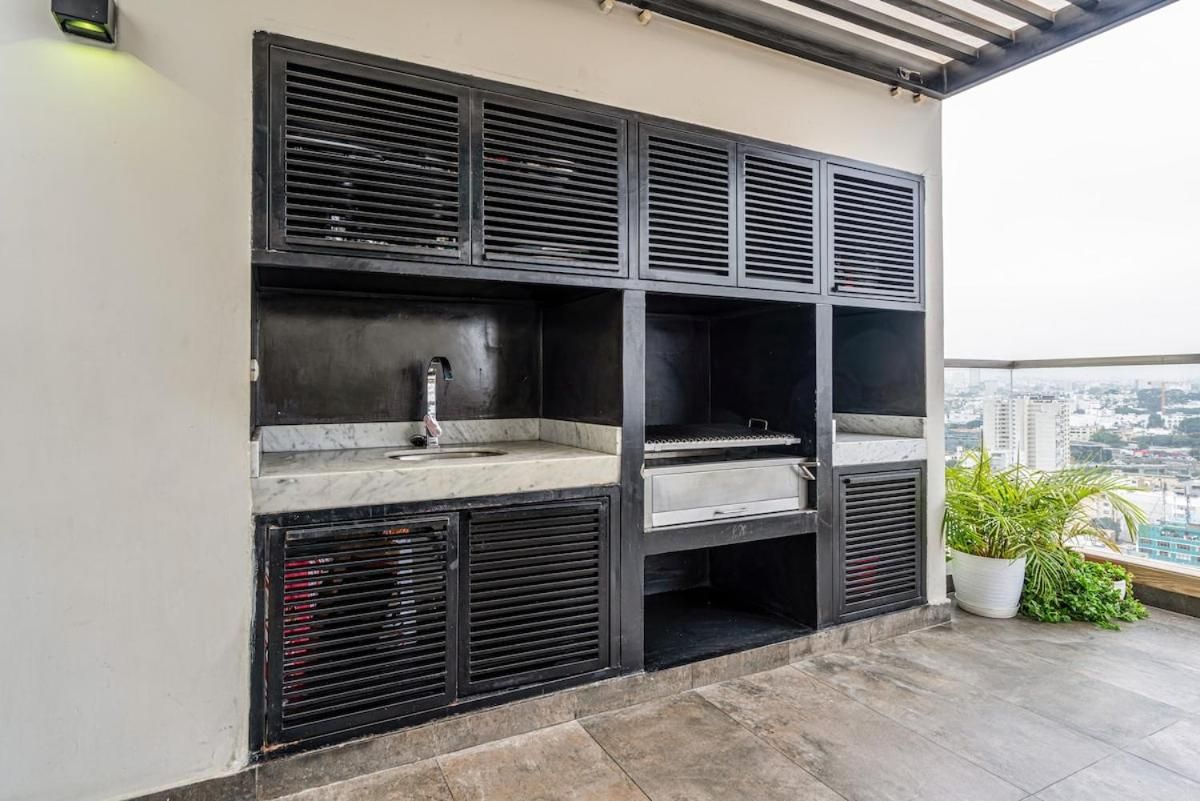 A rooftop bar with a marble countertop, black grill, and a potted plant.