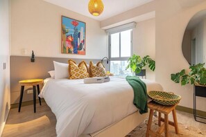 Ein modernes Schlafzimmer mit einem großen Bett, einem Stadtbild, einem Fenster und einer Topfpflanze.