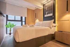 Ein modernes Hotelzimmer mit Bett, Nachttisch und Topfpflanze.