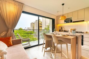 Eine moderne Küche mit Essbereich, großen Fenstern und einem Balkon mit Blick auf Grünflächen.