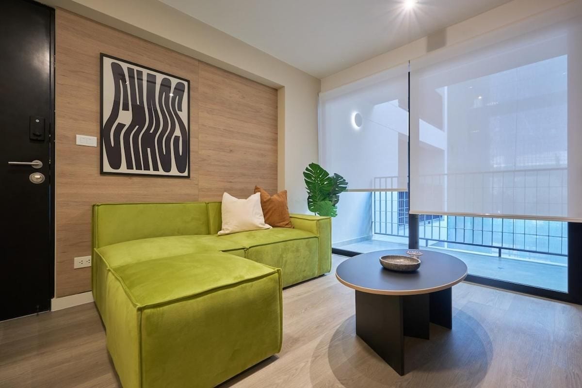 Ein modernes Zimmer mit einem grünen Sofa, einem runden Tisch und einem großen Fenster mit Blick.