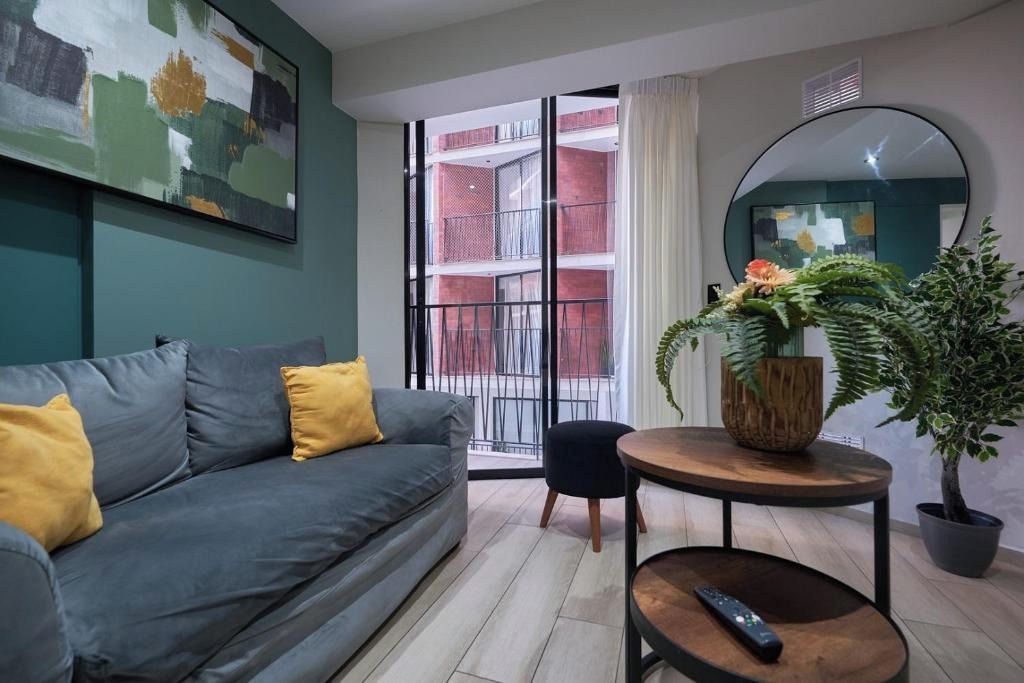 A modern living room with a grey sofa, a round wooden coffee table, and a potted plant.