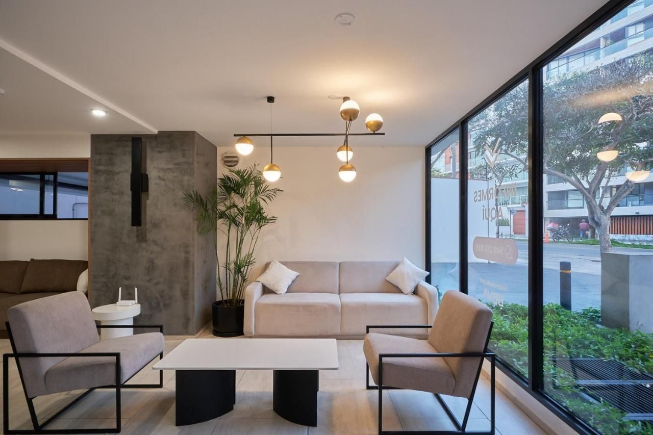 Un intérieur moderne avec un canapé, des fauteuils, une table basse et des luminaires suspendus.