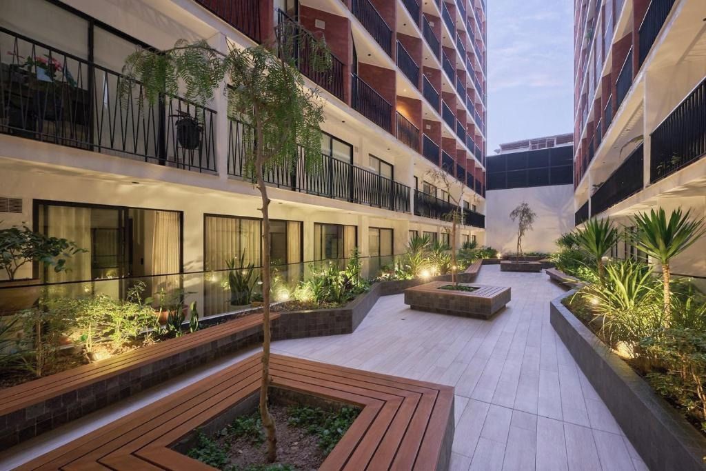 A multi-story hotel with a central courtyard featuring planters, benches, and a small tree.
