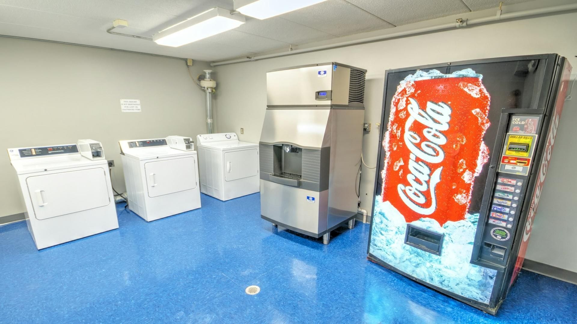 A laundromat with three washers and a Coca-Cola vending machine.