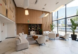 Eine moderne Lobby mit einer Sitzecke, einem Bücherregal und großen Fenstern.
