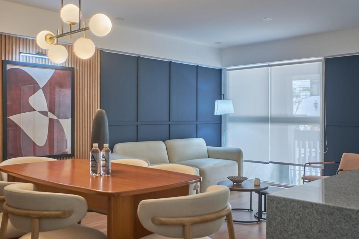 A modern hotel room with a large window, a dining table, and a sofa.