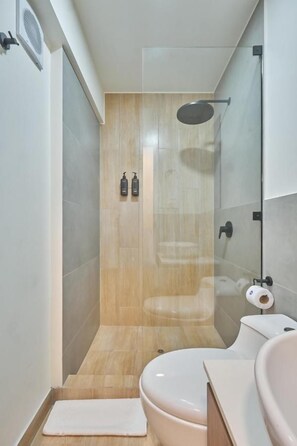 A modern bathroom with a glass-enclosed shower, a toilet, and a sink. - Amador Merino Reyna 346 Residences By Geko (San Isidro)