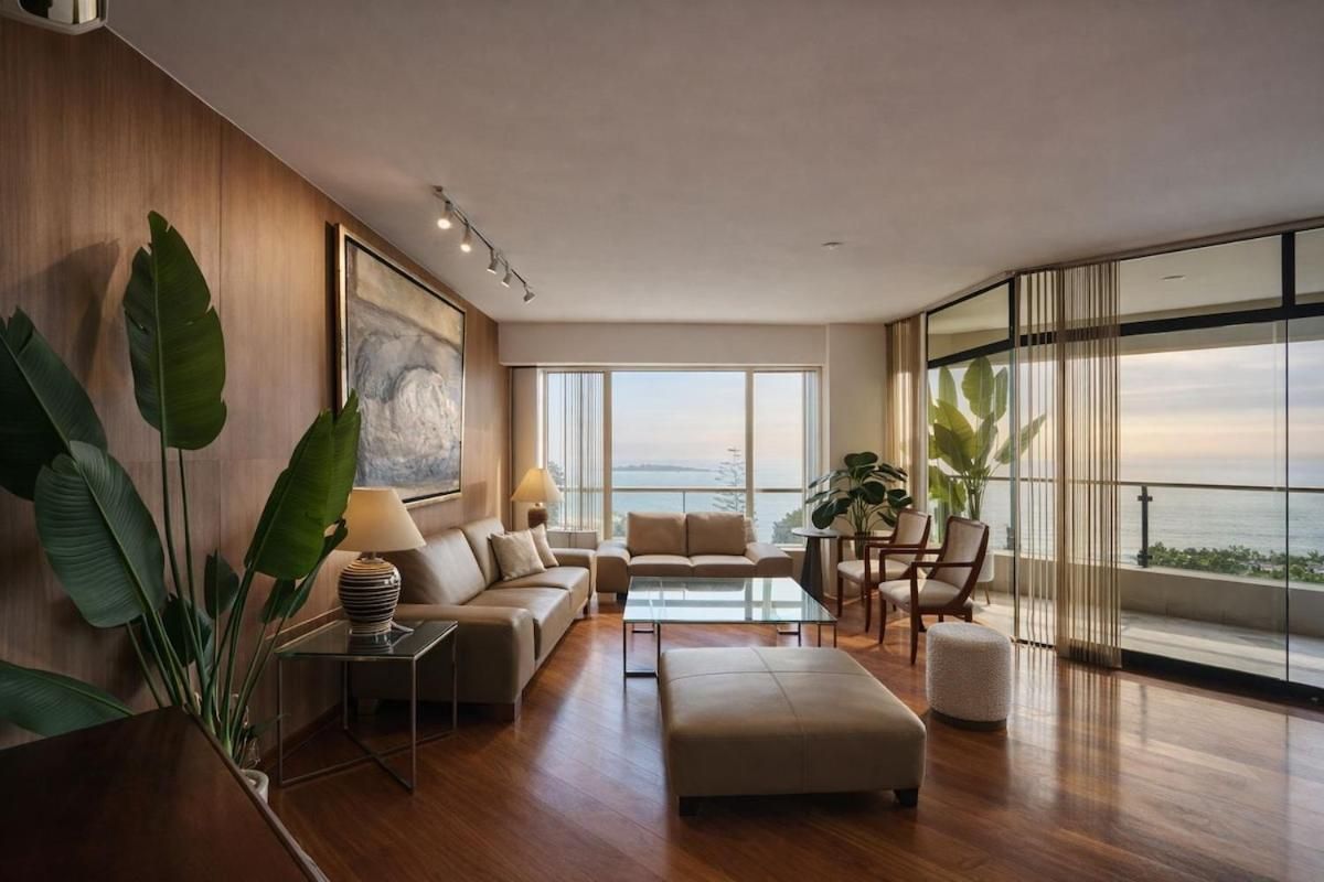 Una sala moderna con un sofá, reposapiés, mesa de centro y vista al océano.