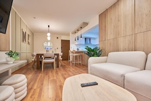Ein modernes Wohnzimmer mit einer Couch, einem Couchtisch und einem Essbereich mit Stühlen und einem Tisch.